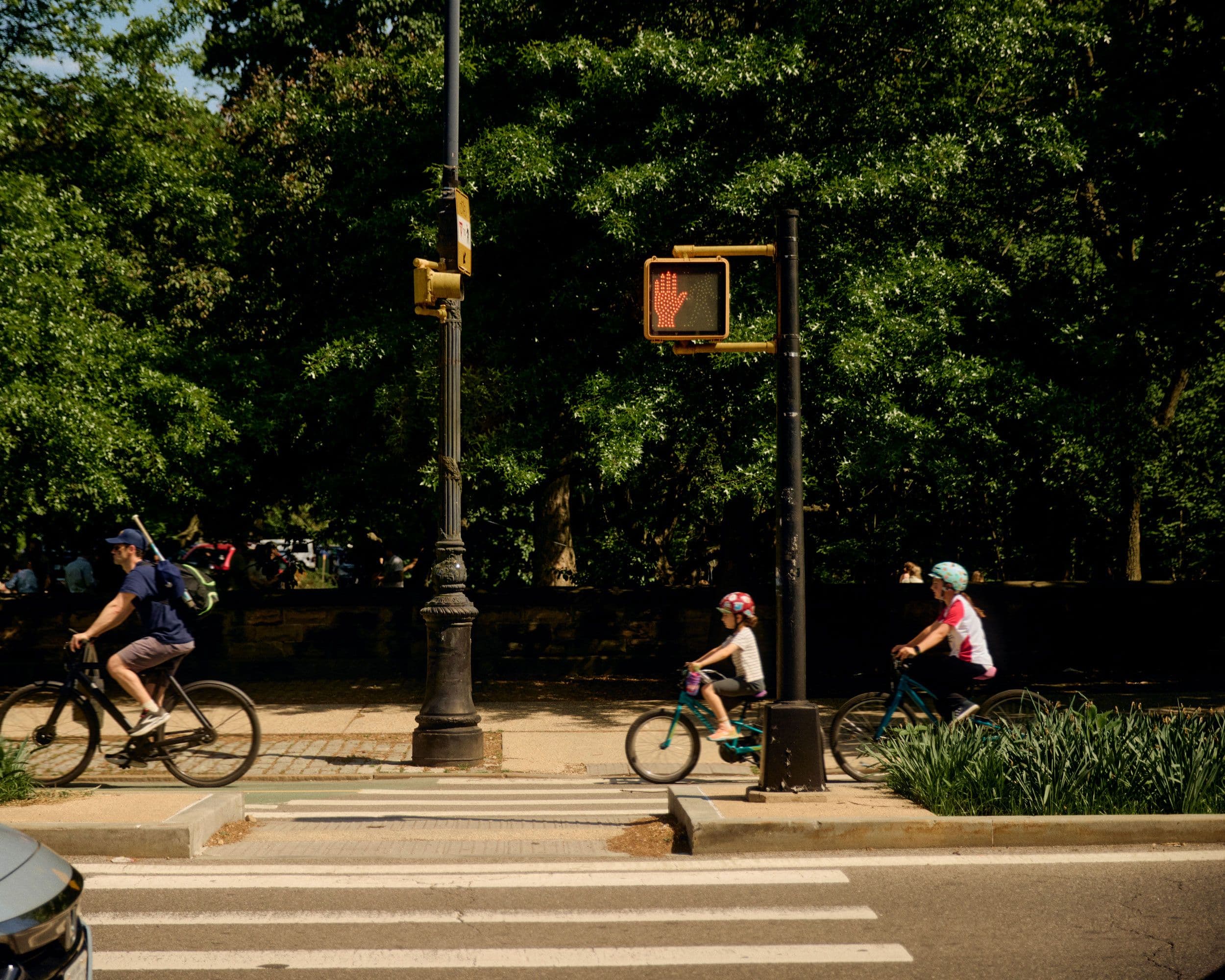 man biking with children behind on bike path near park